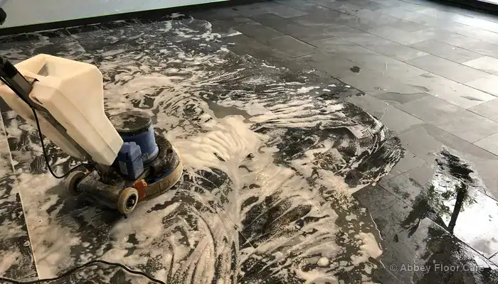 Professional stripping process removing thick liquefied wax slurry from slate tile